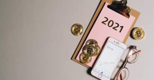 flat lay of bitcoins smartphone eyeglasses and clipboard with 2021 text symbolizing cryptocurren